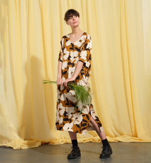 Liebling klänning Sparv i tyget Kokos.&nbsp;Lyxigt enkel kaftanklänning till årets alla fester. Rak modell, v-ringning, sidfickor och slits i sidorna. Obibälte ingår.&nbsp;Bältet är&nbsp;lätt vadderat och passar även fint att ha till annat:) Tyget är lite blankt vilket ger en extra lyxig känsla!&nbsp;

Färg: Vita blommor och svarta blad på guldbrun botten.

Material: 51% EcoVero, 49% viskos från Frankrike. 
Designad i Malmö, sydd i Litauen