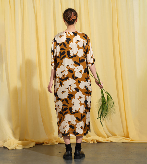 Liebling klänning Sparv i tyget Kokos.&nbsp;Lyxigt enkel kaftanklänning till årets alla fester. Rak modell, v-ringning, sidfickor och slits i sidorna. Obibälte ingår.&nbsp;Bältet är&nbsp;lätt vadderat och passar även fint att ha till annat:) Tyget är lite blankt vilket ger en extra lyxig känsla!&nbsp;

Färg: Vita blommor och svarta blad på guldbrun botten.

Material: 51% EcoVero, 49% viskos från Frankrike. 
Designad i Malmö, sydd i Litauen