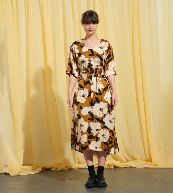 Liebling klänning Sparv i tyget Kokos.&nbsp;Lyxigt enkel kaftanklänning till årets alla fester. Rak modell, v-ringning, sidfickor och slits i sidorna. Obibälte ingår.&nbsp;Bältet är&nbsp;lätt vadderat och passar även fint att ha till annat:) Tyget är lite blankt vilket ger en extra lyxig känsla!&nbsp;

Färg: Vita blommor och svarta blad på guldbrun botten.

Material: 51% EcoVero, 49% viskos från Frankrike. 
Designad i Malmö, sydd i Litauen