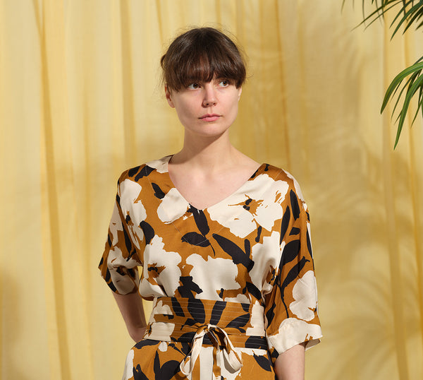 Liebling klänning Sparv i tyget Kokos.&nbsp;Lyxigt enkel kaftanklänning till årets alla fester. Rak modell, v-ringning, sidfickor och slits i sidorna. Obibälte ingår.&nbsp;Bältet är&nbsp;lätt vadderat och passar även fint att ha till annat:) Tyget är lite blankt vilket ger en extra lyxig känsla!&nbsp;

Färg: Vita blommor och svarta blad på guldbrun botten.

Material: 51% EcoVero, 49% viskos från Frankrike. 
Designad i Malmö, sydd i Litauen