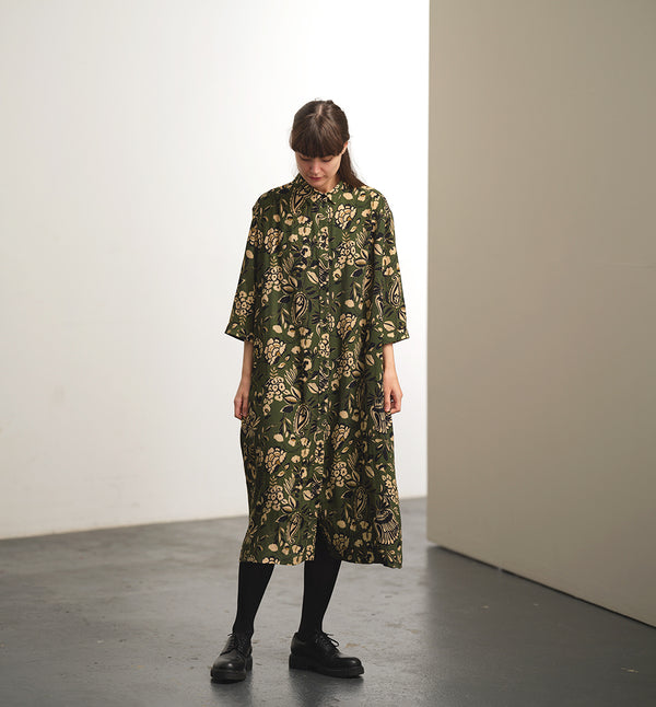 klänning Svala Lotus. En ankellång skjortklänning med lös passform, trekvartsärm och fickor i sidorna. Ok med rynk i ryggen. Ett 2,5 cm brett band i samma tyg medföljer och kan knytas i midjan. Svala är fin både öppen och stängd, med eller utan band. Svarta knappar mitt fram och vid ärmslut. Sydd i en fin viskos.

Svala&nbsp;är generös i storleken,&nbsp;välj gärna en storlek mindre än du brukar.
Se måttabell nedan.

Färg: Blommor i beige, svart och gulgrönt på grön botten.

Material:&nbsp; EcoVero