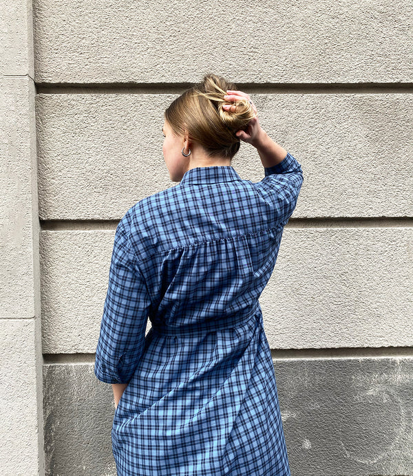 Vår klänning Svala. En ankellång skjortklänning med lös passform, trekvartsärm och fickor i sidorna. Ok med rynk i ryggen. Ett 2,5 cm brett band i samma tyg medföljer och kan knytas i midjan. Svala är fin både öppen och stängd, med eller utan band. Svarta knappar mitt fram och vid ärmslut. Sydd i ett deadstock tyg.&nbsp;

Färg: Svart och blårutig
Material: 100% bomull
Designad i Malmö, sydd i Litauen