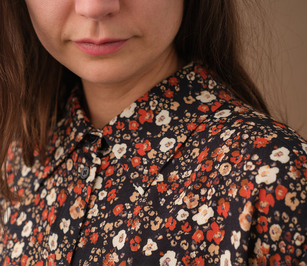 Lieblings skjorta Unni. Unni är en vid skjorta med armbågslång ärm. Ok med veck i ryggen. Lätt rundad bak. Sydd i en ekologisk viskos.

Färg: Små blommor i beige, vitt och orange på svart botten. Svart band.

Material:&nbsp;51% EcoVero, 49% viskos från Frankrike.