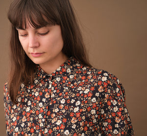 Lieblings skjorta Unni. Unni är en vid skjorta med armbågslång ärm. Ok med veck i ryggen. Lätt rundad bak. Sydd i en ekologisk viskos.

Färg: Små blommor i beige, vitt och orange på svart botten. Svart band.

Material:&nbsp;51% EcoVero, 49% viskos från Frankrike.