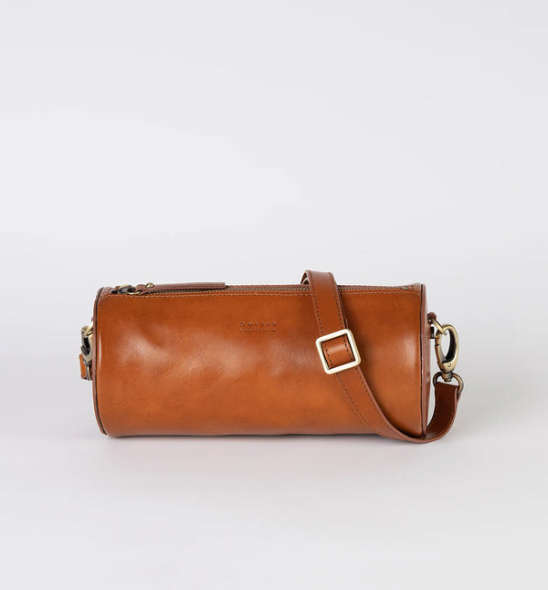 Handväska Izzy är O My Bag:s unika cylinderformade handväska som förkroppsligar den där edgy och retro, men ändå minimalistiska stilen. Denna cross-body-väska är tillverkad av hållbart ekologiskt läder. Den justerbara remmen gör att den kan bäras på olika sätt, som en cross-body-väska eller kortare för ett elegant axelalternativ.
Material:&nbsp; Lädret är av högsta kvalitet och garvat utan användning av skadliga kemikalier. Färg: konjaksbrun