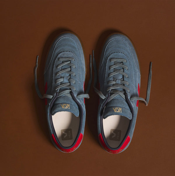 Sneakers Paneka från Veja! Designen är en blandning av fotbollsarv och urban kultur.

Färg: Gråblå med röda detaljer

Ovandel: Mocka

Paneler: Mocka och ekologiskt spårat läder (O.T.)
Logotyp V: Mocka